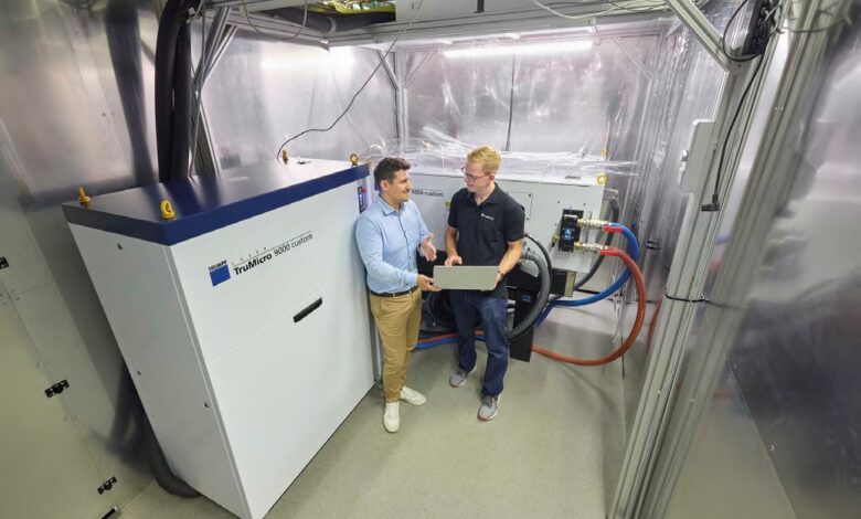 Steffen Rübling, TRUMPF (a sinistra), e il dott. Dennis Haasler, Fraunhofer ILT, discutono i dettagli del funzionamento del laser UKP da 1 kW di TRUMPF.