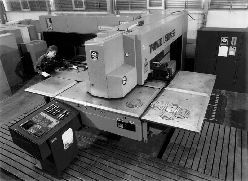 Sistema combinato laser punzone presentato alla EMO di Milano nel 1979. In alto a sinistra si vede la sorgente a CO2 da 500 W a flusso assiale lento utilizzata: si confrontino le dimensioni con quelle della sorgente nella figura della pagina successiva avente potenza 200 volte maggiore.