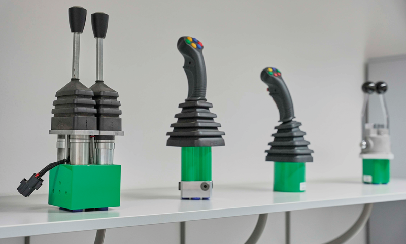 La gamma di joystick di Hydreco Hydraulics: in primo piano il mini-joystick elettrico proporzionale MHDC, con impugnatura MHC.